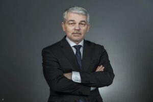 Carlo Masala im Anzug mit verschränkten Armen vor neutralem Hintergrund – Experte für internationale Politik